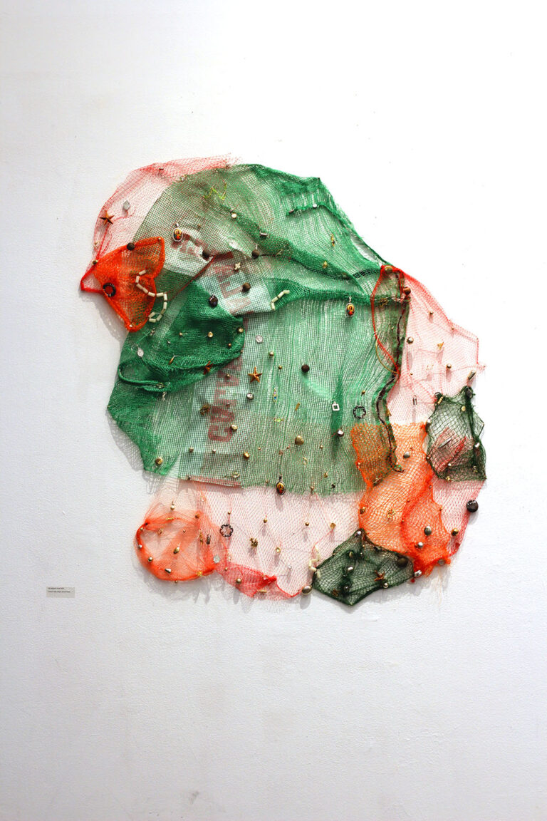 Beads and nets sewn together in a patchwork pattern of red, black, and green.