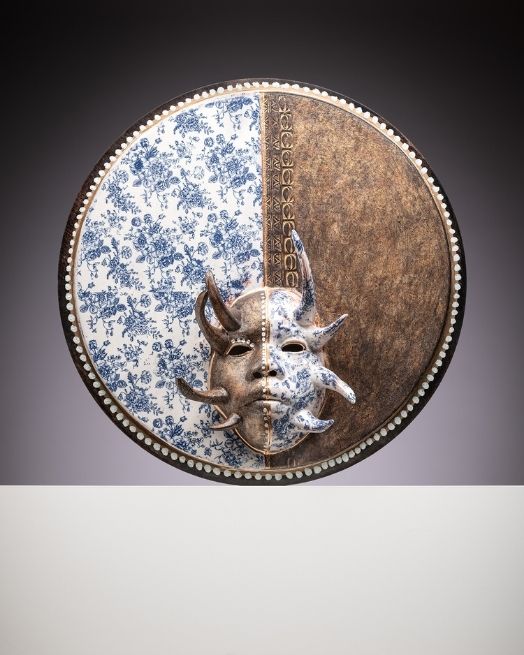 Eyeless mask with a rounded halo connected around the perimeter. The mask is split in half vertically with two different textiles.