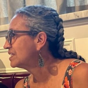 Artist Sara Morales photographed by Esperanza Martell. Profile view of woman with braided hair and glasses.