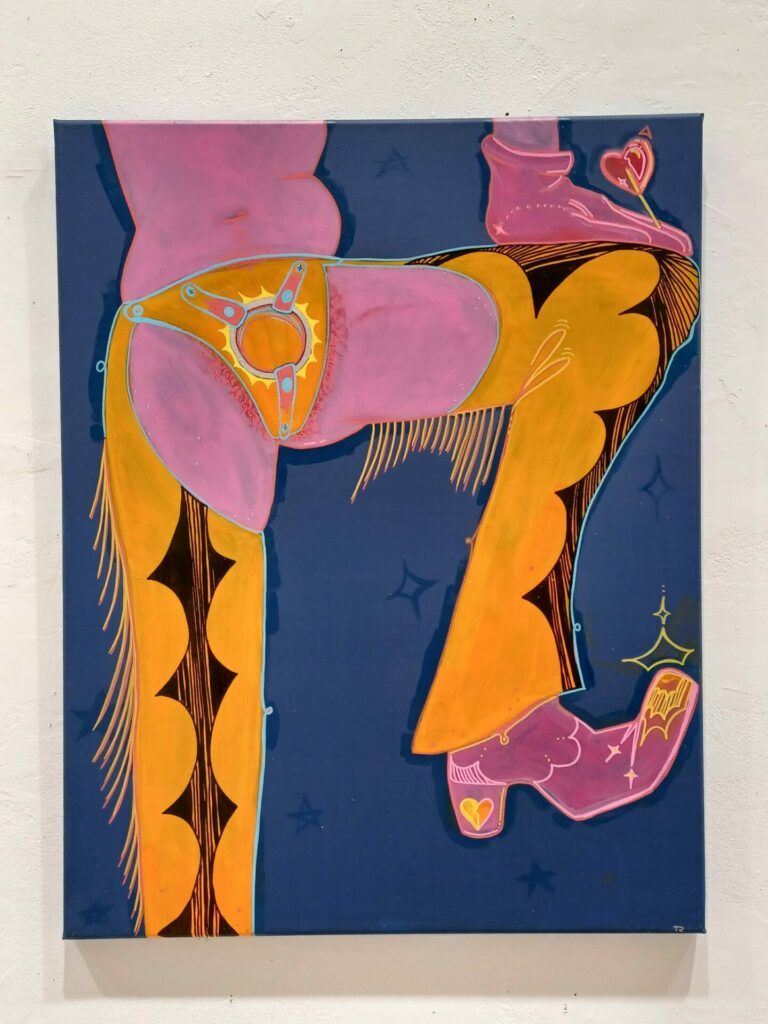 The lower half of a body, dressed in cowboy chaps. The chaps are worn with a strap-on. The person holds a heart-shaped lollipop.